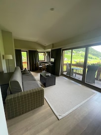 Grosses Wohnzimmer mit Erker Sitzplatz und Tisch, grosses Sofa und 2 Balkonen ins Grüne. Sehr gutes WLAN