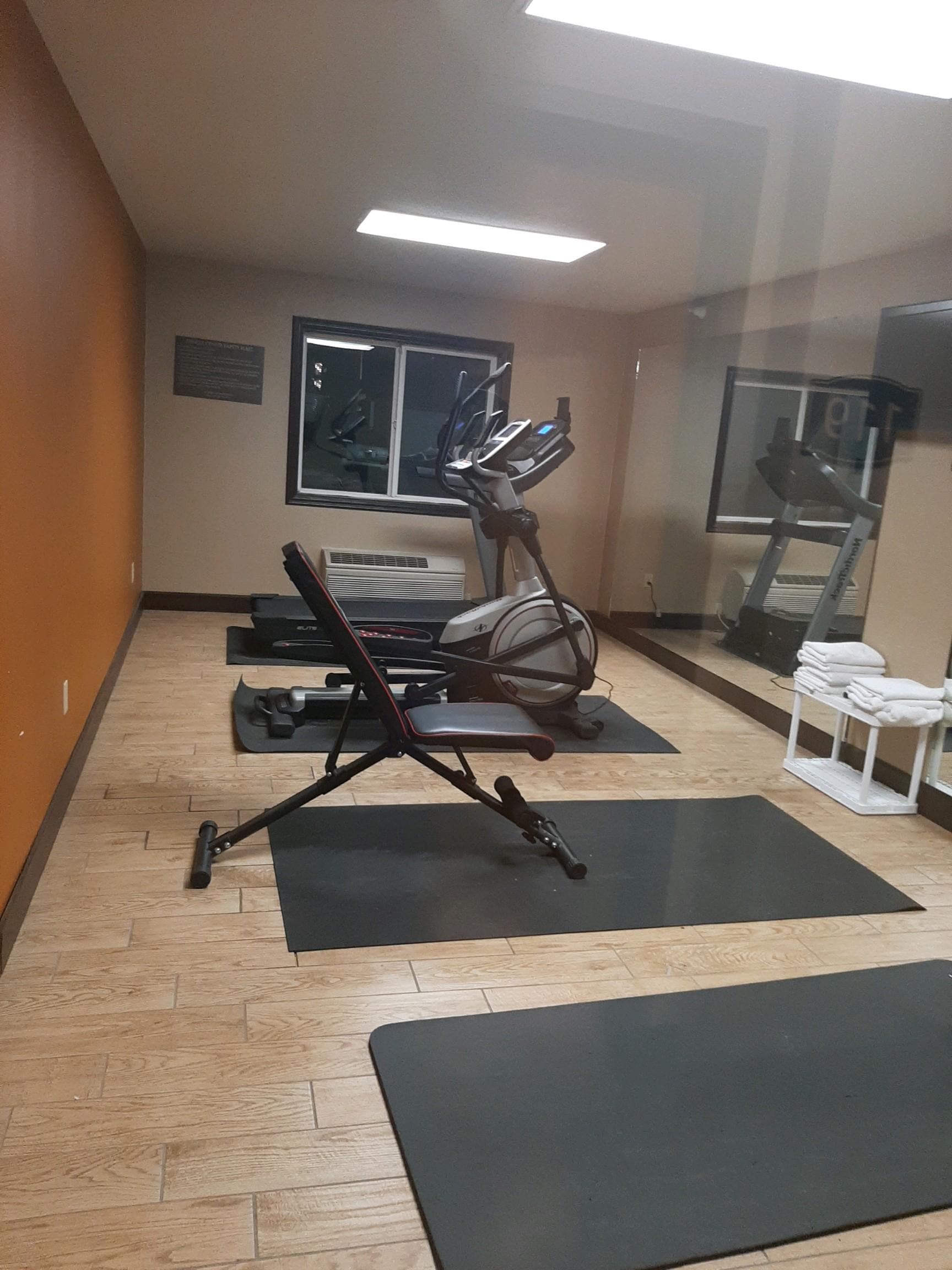 The REAL look of their Fitness Room.  1 Treadmill, 1 Eliptical, and 1 cheap home gym weight bench, but not even one dumbbell in there.
