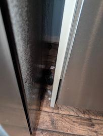 trash between fridge and dishwasher