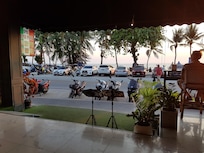 Sitting on high chair at long table looking out to the road and beach as the sun goes down.