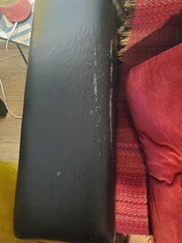 Sofa with scratch marks and holes covered up by a rug