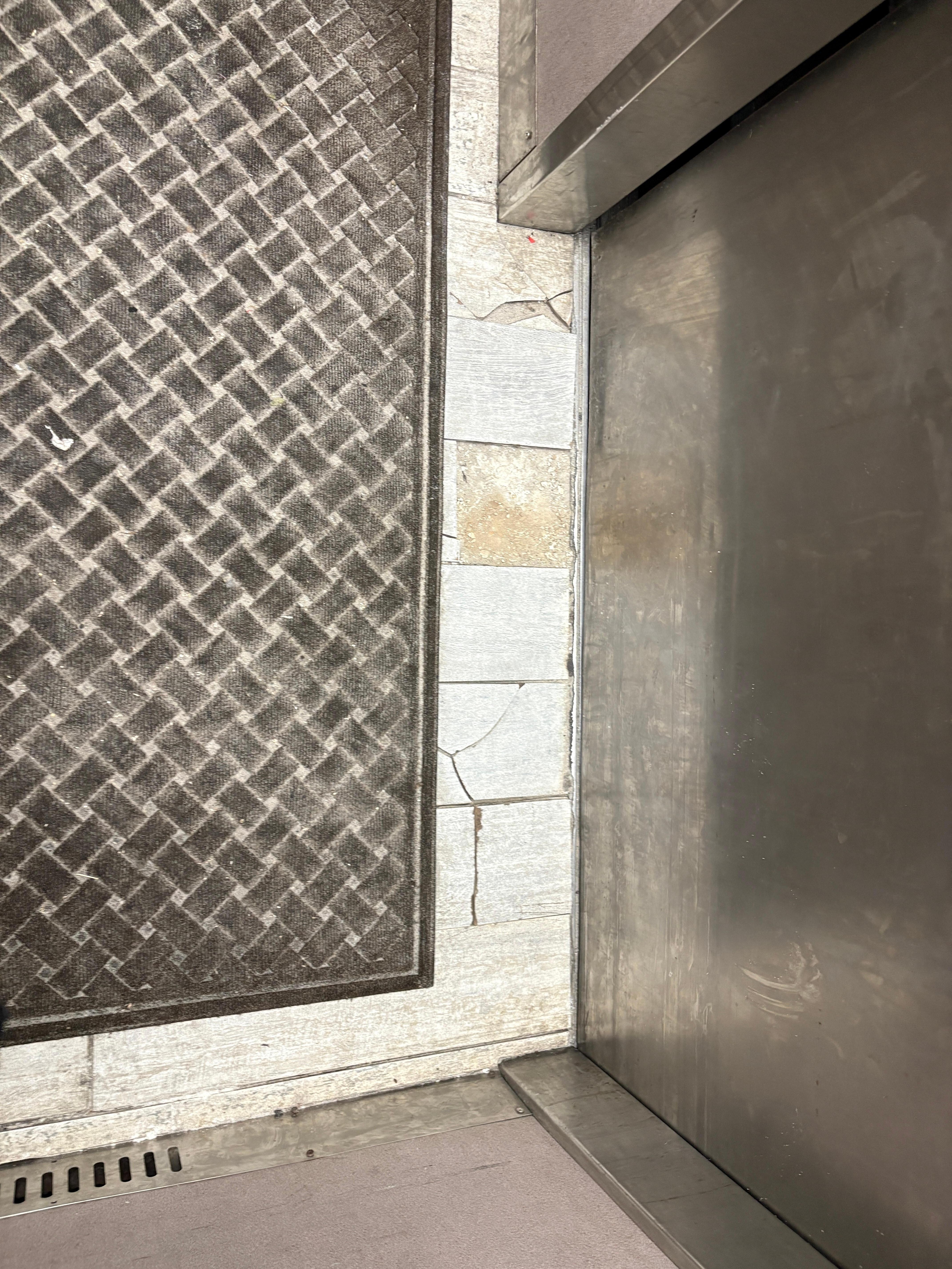 Busted elevator tiles with a rug thrown over them.