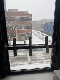 Window had to be duct taped closed because it flopped open. Note the snow outside. No one ever came to repair despite contacting the property manager. We did the duct taped closed repair. Back bedrooms were COLD!