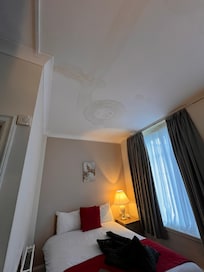 Wide shot of the water damage and cracks in ceiling directly above bed