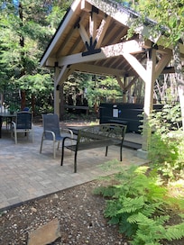 Fenced back patio is surrounded by forest