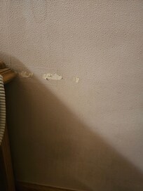 Stained damaged wall next to bed