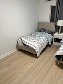 One of two twin beds with flat sheet and comforter only