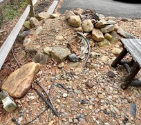 Outdoor fire pit made of loose rocks with exposed plastic tubing.