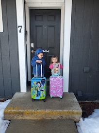 Brother convincing sister they should hurry and go in to see their room in the house.