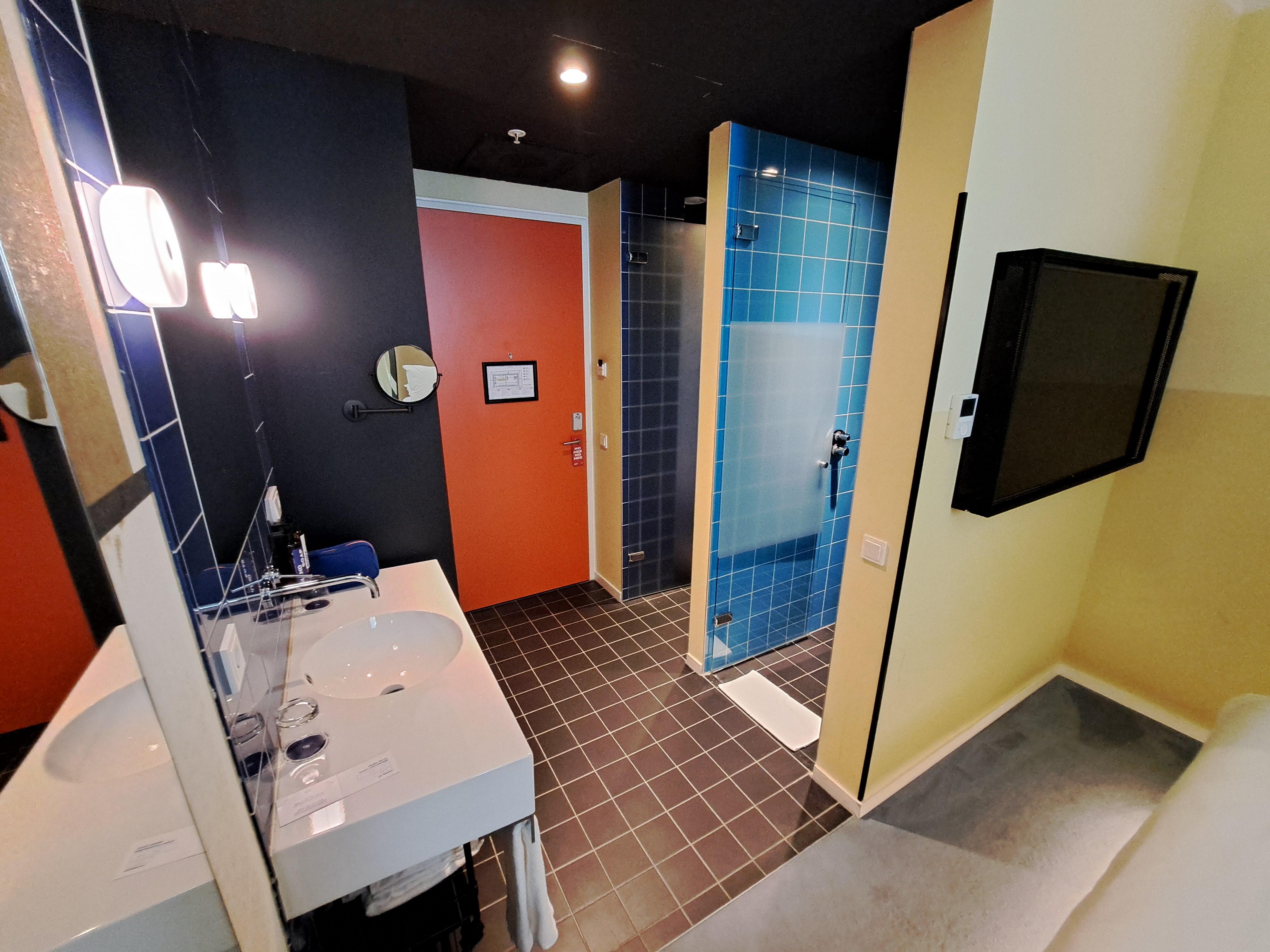 Room 274 entrance area with sink, wardrobe, entrance door, toilet cubicle, walk-in shower cubicle, air-conditioning controller and television.