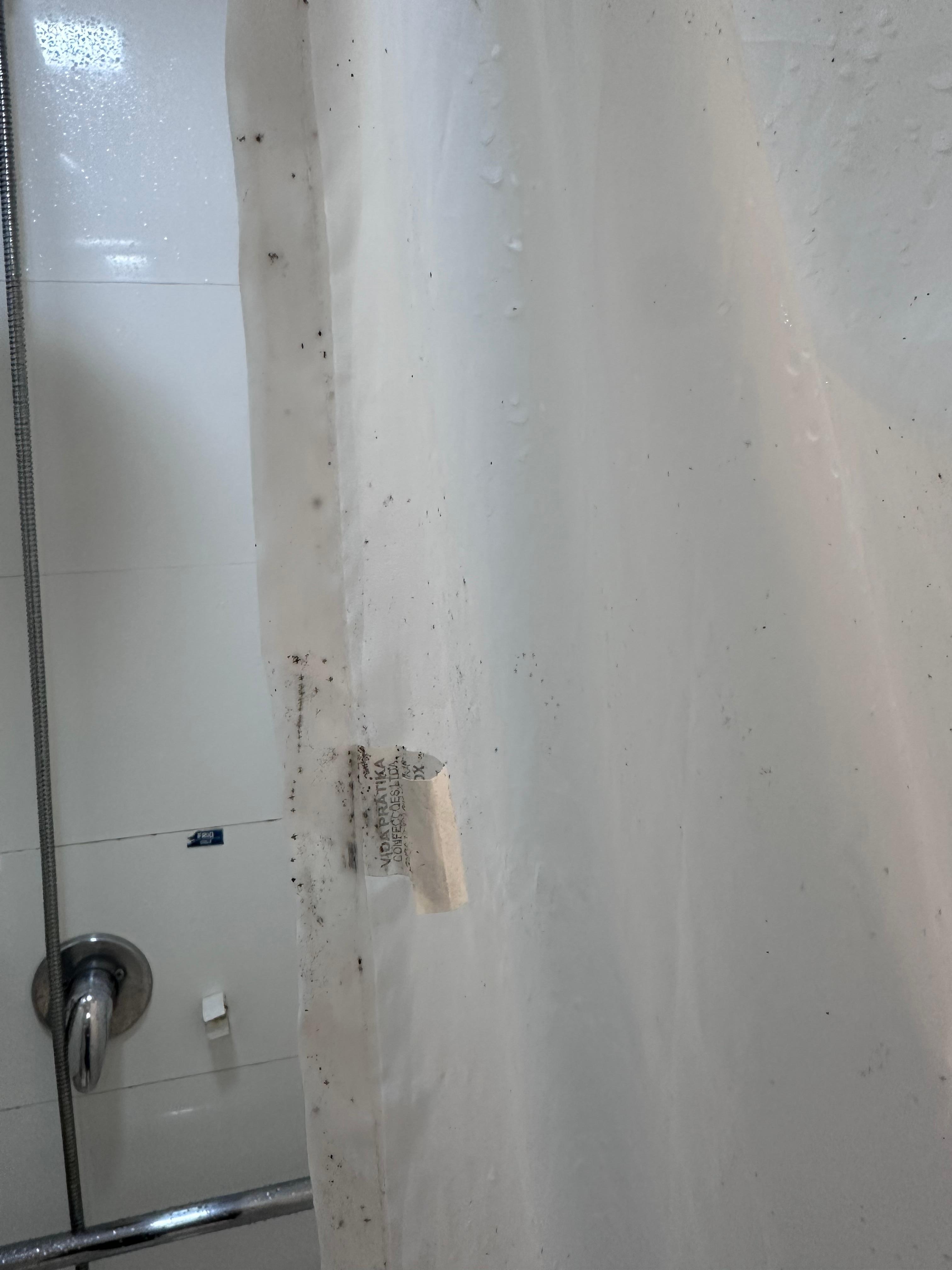 Banheiro sem box e com cortina velha e cheia de mofo