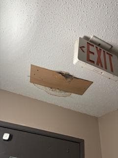 One of many holes in the ceiling covered with plywood