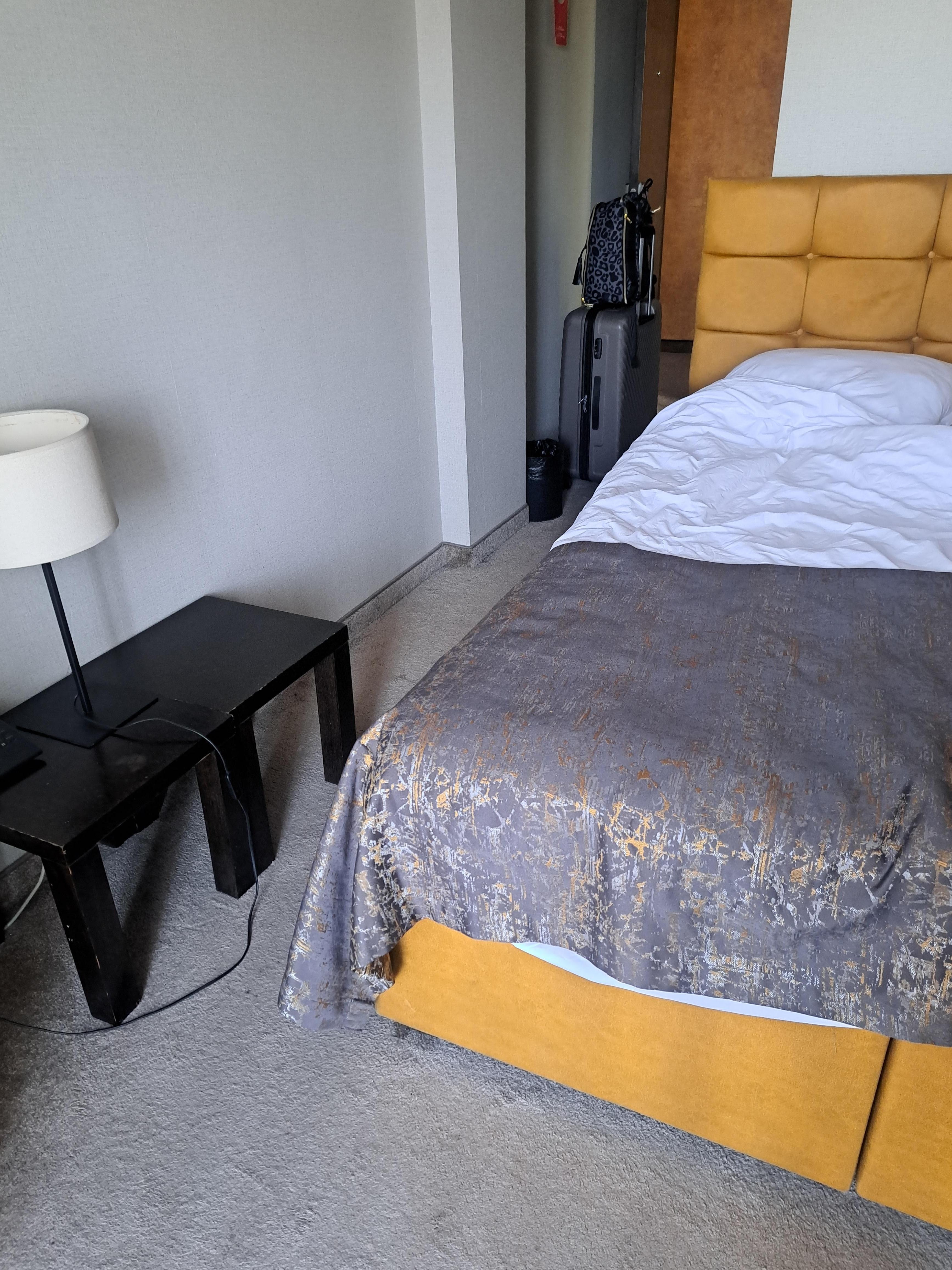 A double bed with a single duvet and no bedside table or access to a light from the bed. Bed too hig for the room.