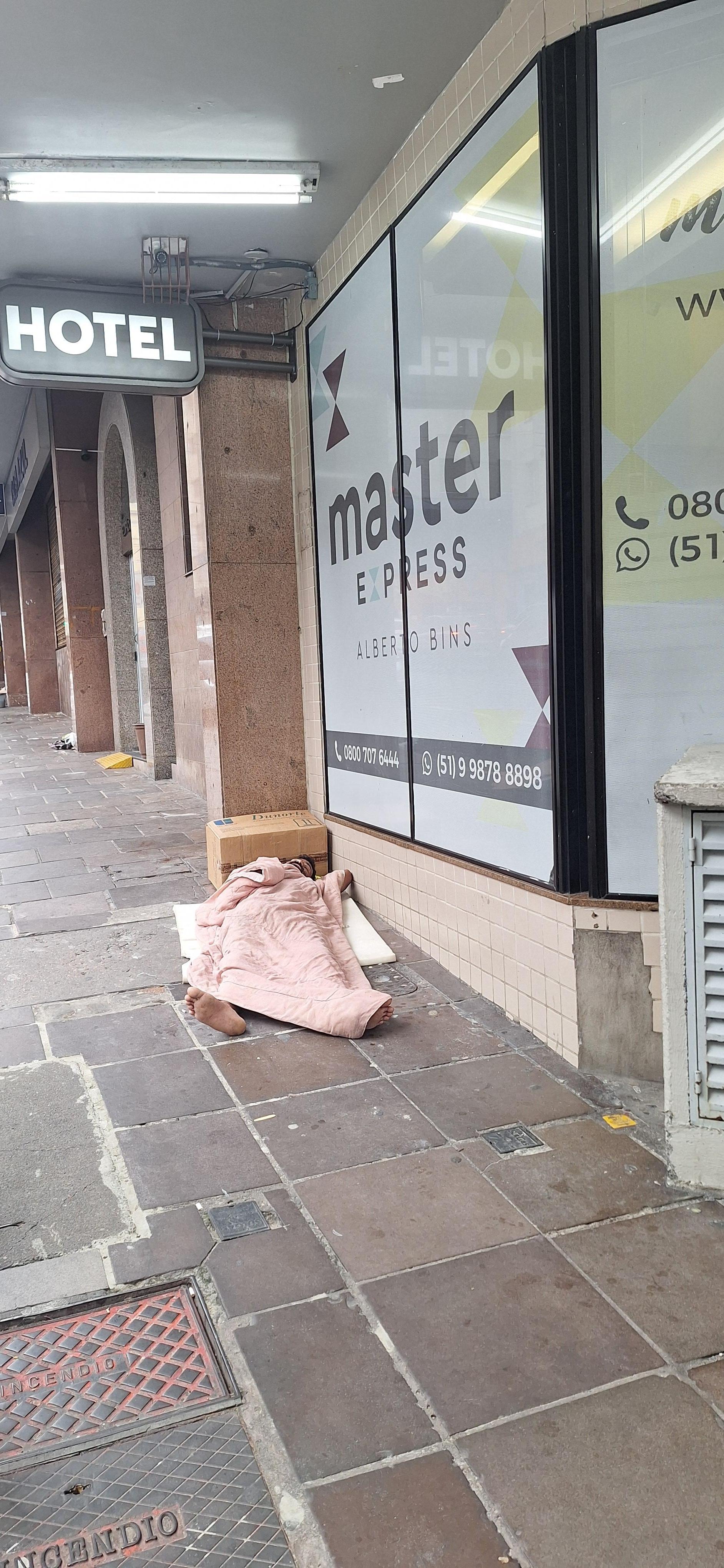 Mendigo dormindo na entrada do hotel.