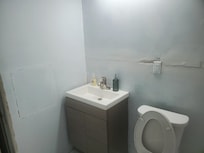 One of the downstairs bathrooms as an example of what three other bathrooms look like. Hanging pocket doors with no molding, early stages of renovation, unsafe electricals.