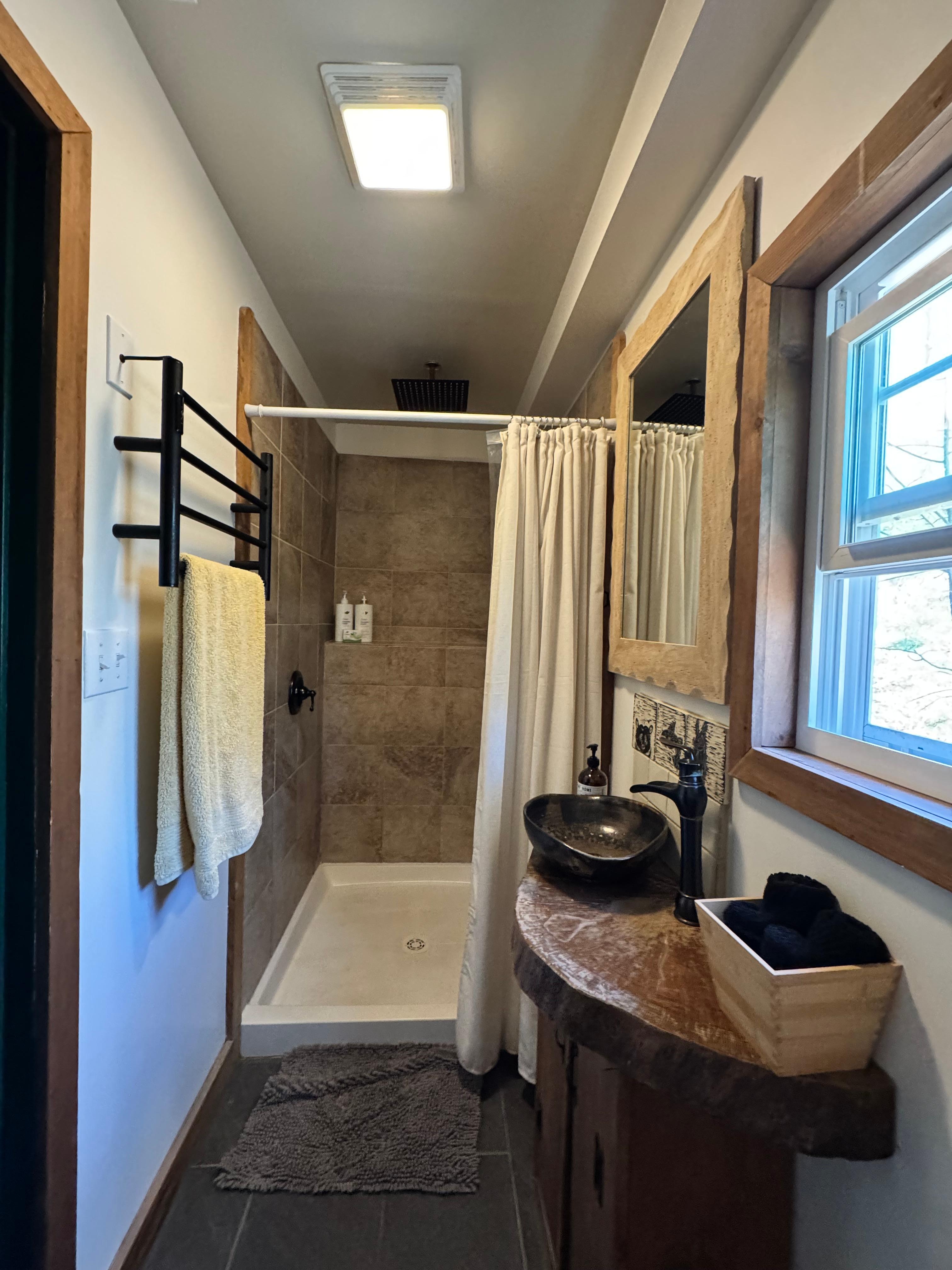 Bathroom with rainfall shower head and towel warmer