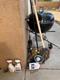 This is the small grill in back yard with spray bottles & charcoal fluid just laying there.