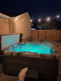 Hot tub at night with various lights in the tub - note the little water features on the opposite ends. Great jets too.