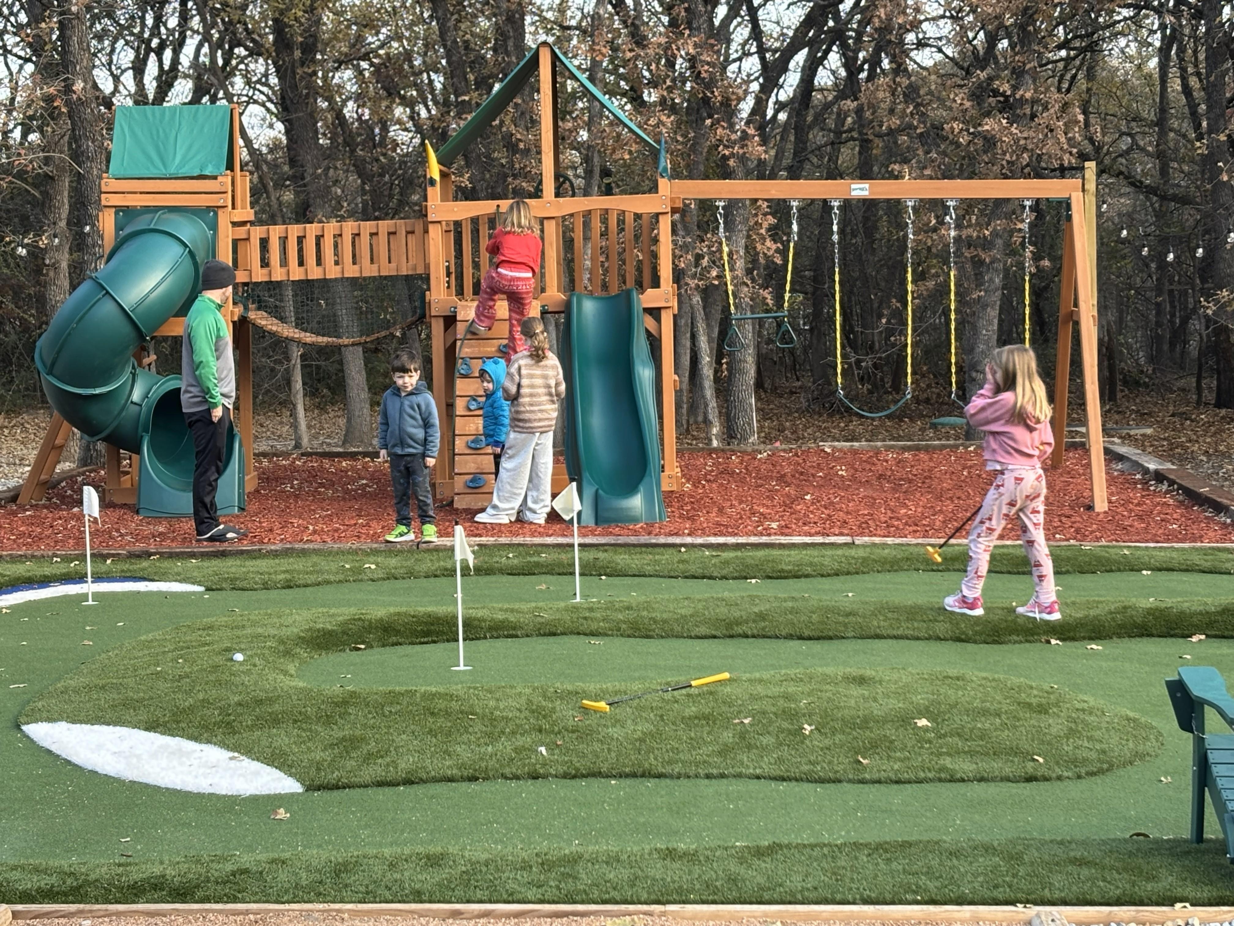 Putting green and playground enjoyed by kids