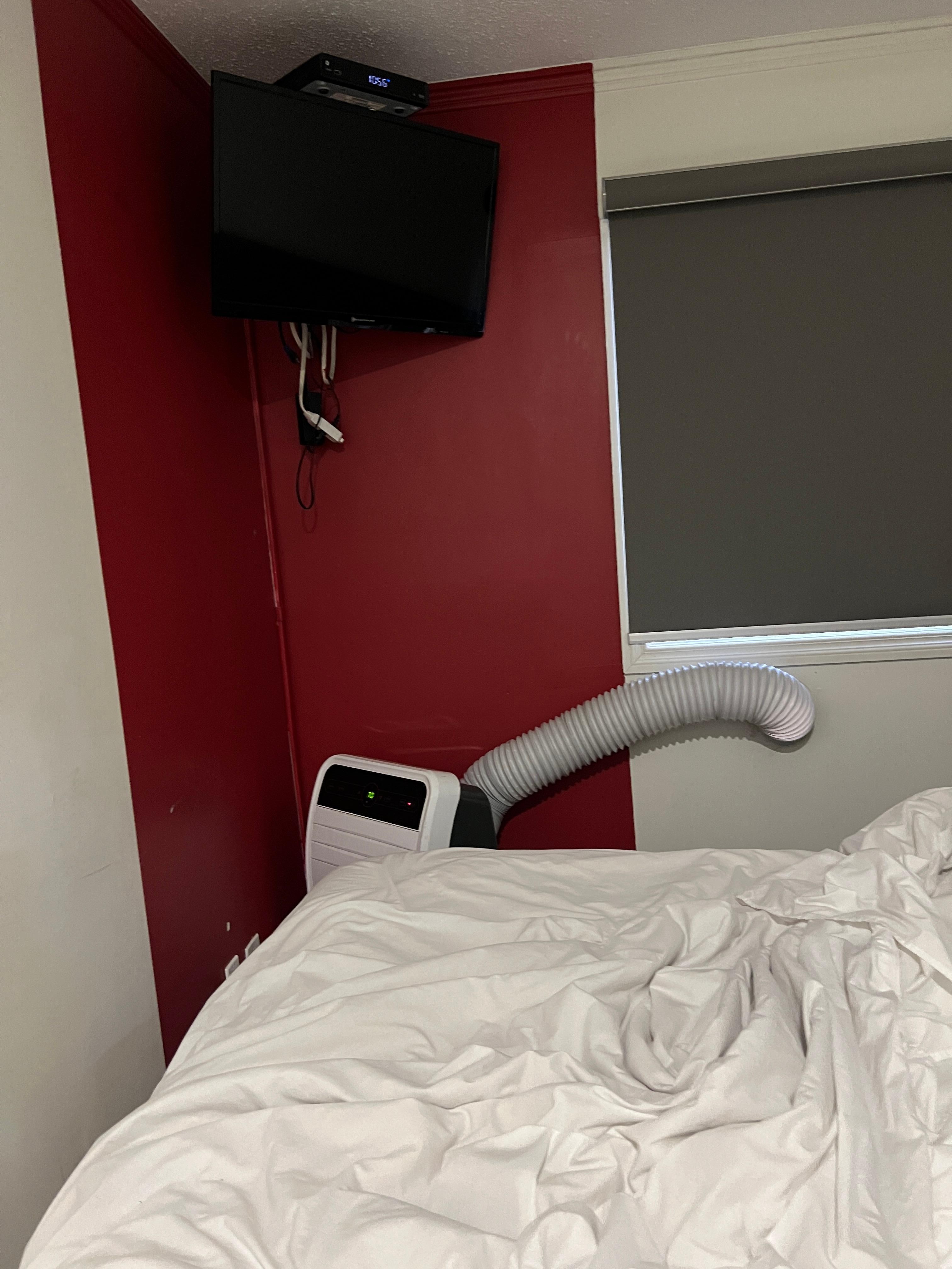 Portable air conditioner air intake hose drilled into bedroom wall