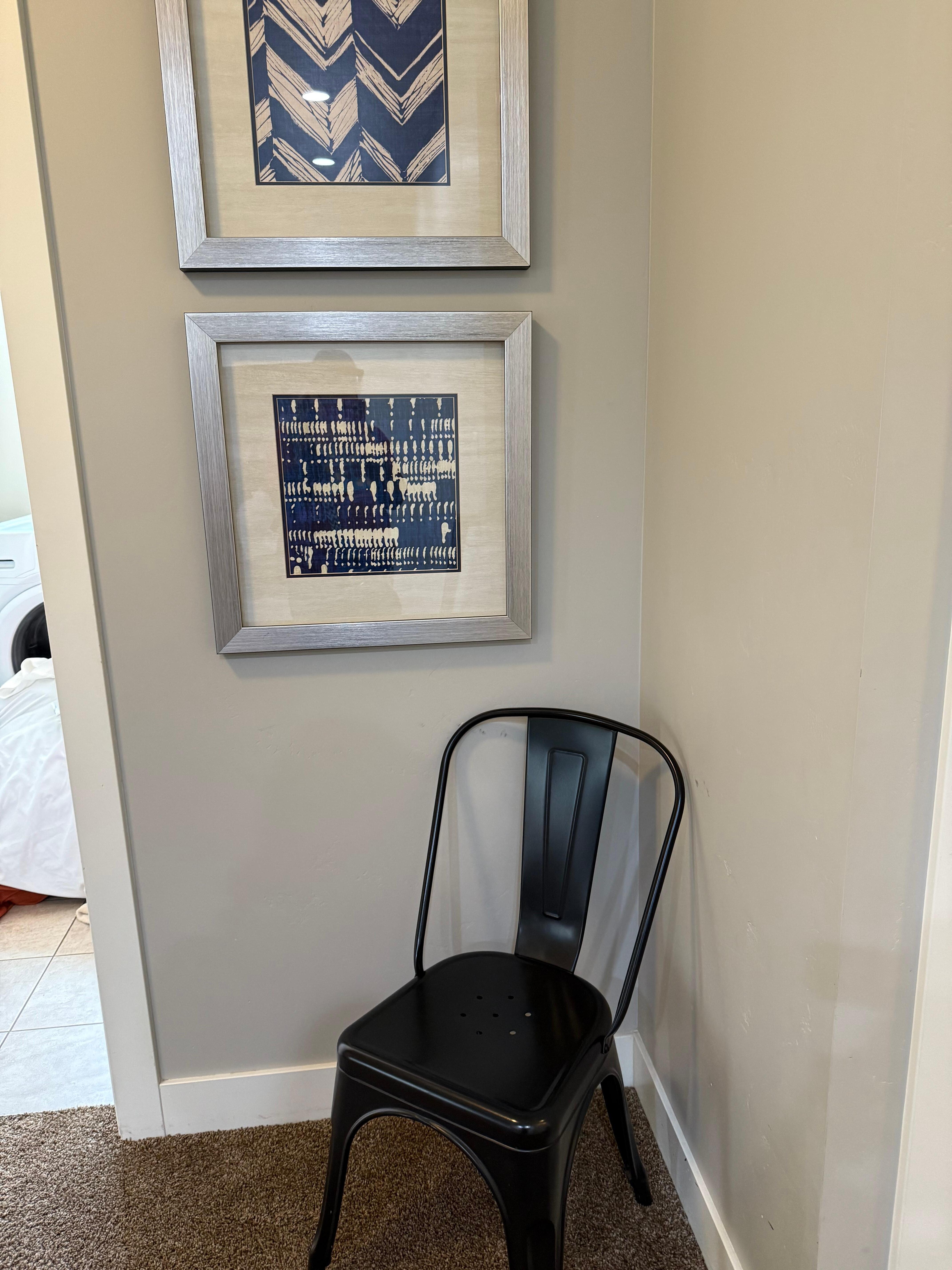 A chair next to the laundry room under some nice art.