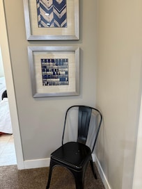 A chair next to the laundry room under some nice art.