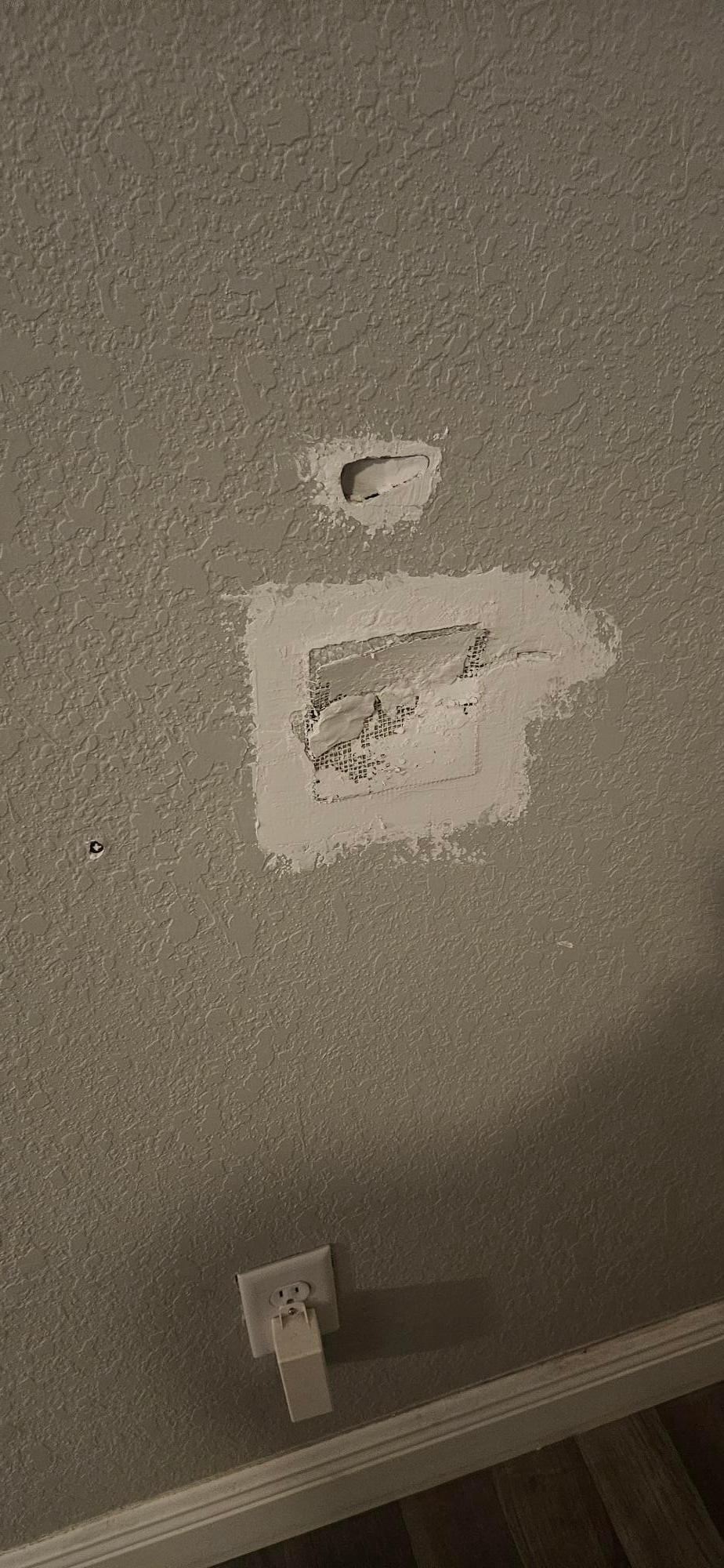 Hole in wall behind front door caused by doorknob striking wall.