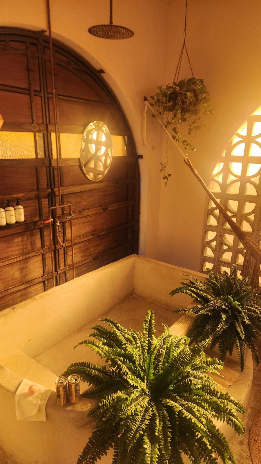 concrete soaking tub with rainfall shower, this is in an open air bathroom through a door in the bedroom. 