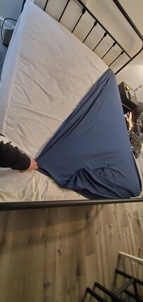 Trying to fit a replacement standard sized sheet on the double bed in the room.