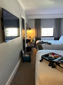 Room missing dresser, accent chair and coffee maker. Bed only inches from wall.