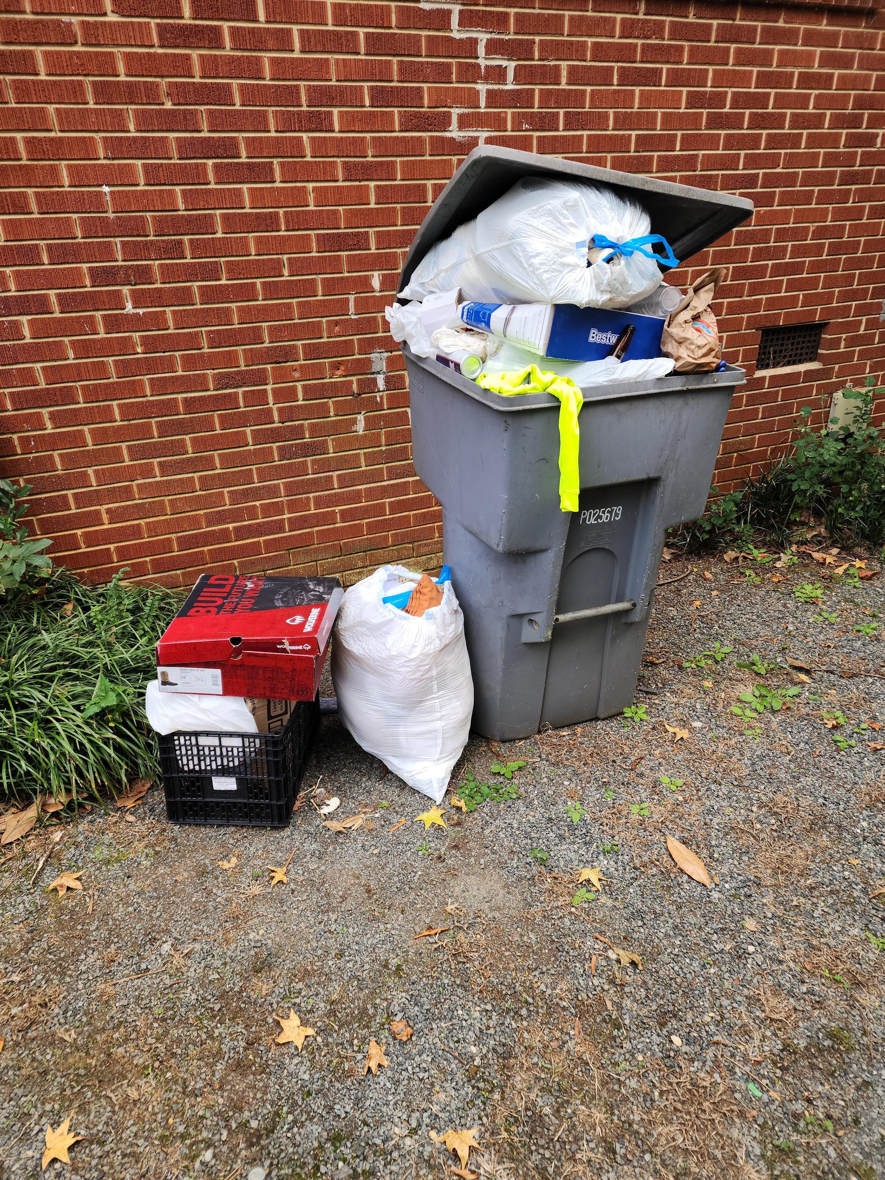 One of two overflowing trashcans by the house
