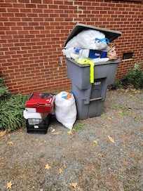 One of two overflowing trashcans by the house