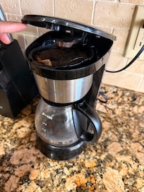 Dirty coffee pot filled with used coffee grounds and they were dirty pots and silverware and we clean dishes