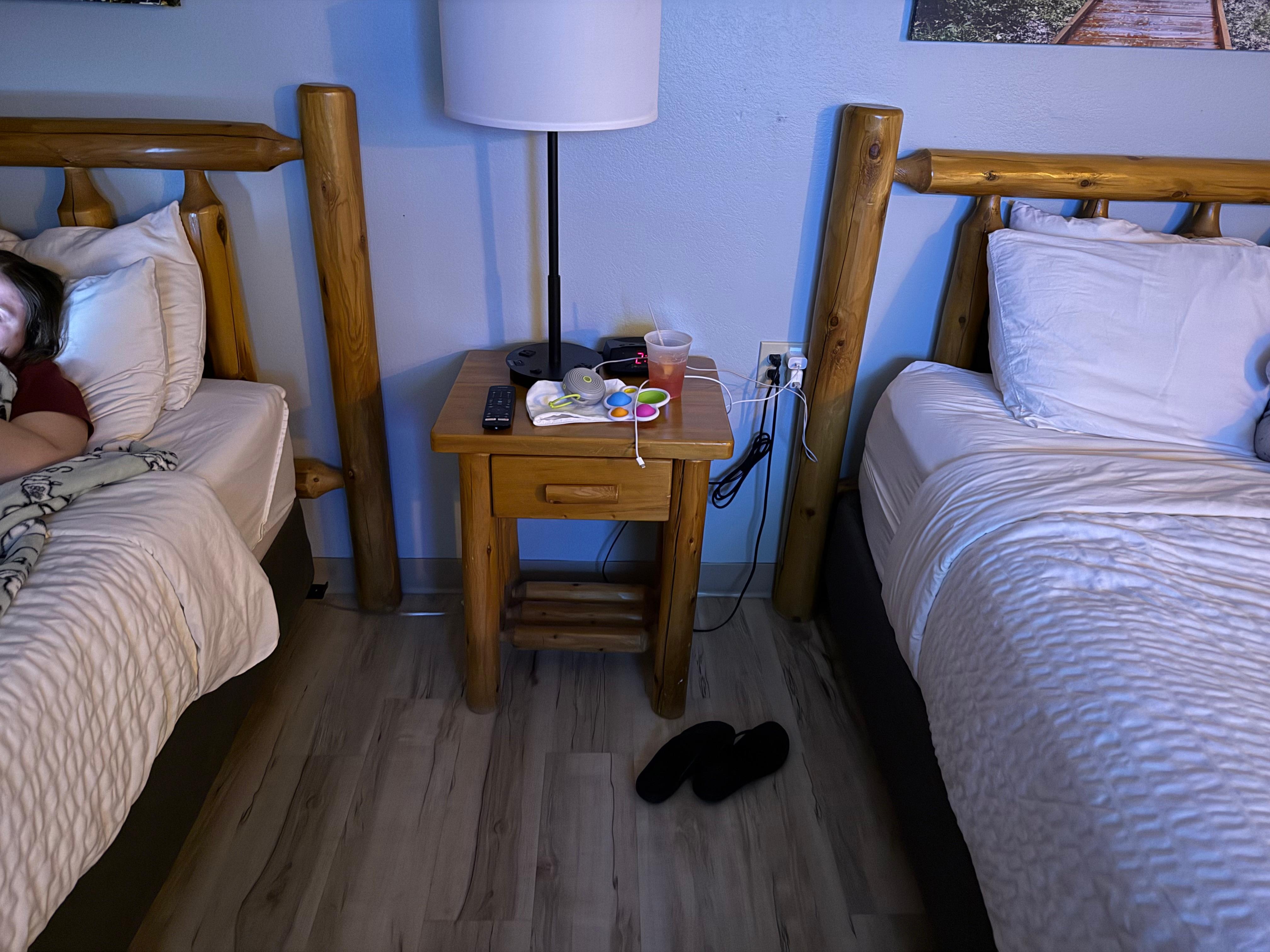 One small end table for 2 queen beds. Head boards not attached to bed, just leaning on wall. Beds easily push away from headboard. 