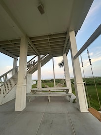 Bottom sitting area. Hammock, swings, exterior shower, picnic table, spacey backyard area. Stairs that lead to first porch (balcony) with hot tub and sitting area. There is a high balcony out of the master bedroom that also hosts such a view.