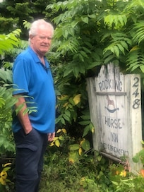 My husband by the Rocky Horse Inn sign