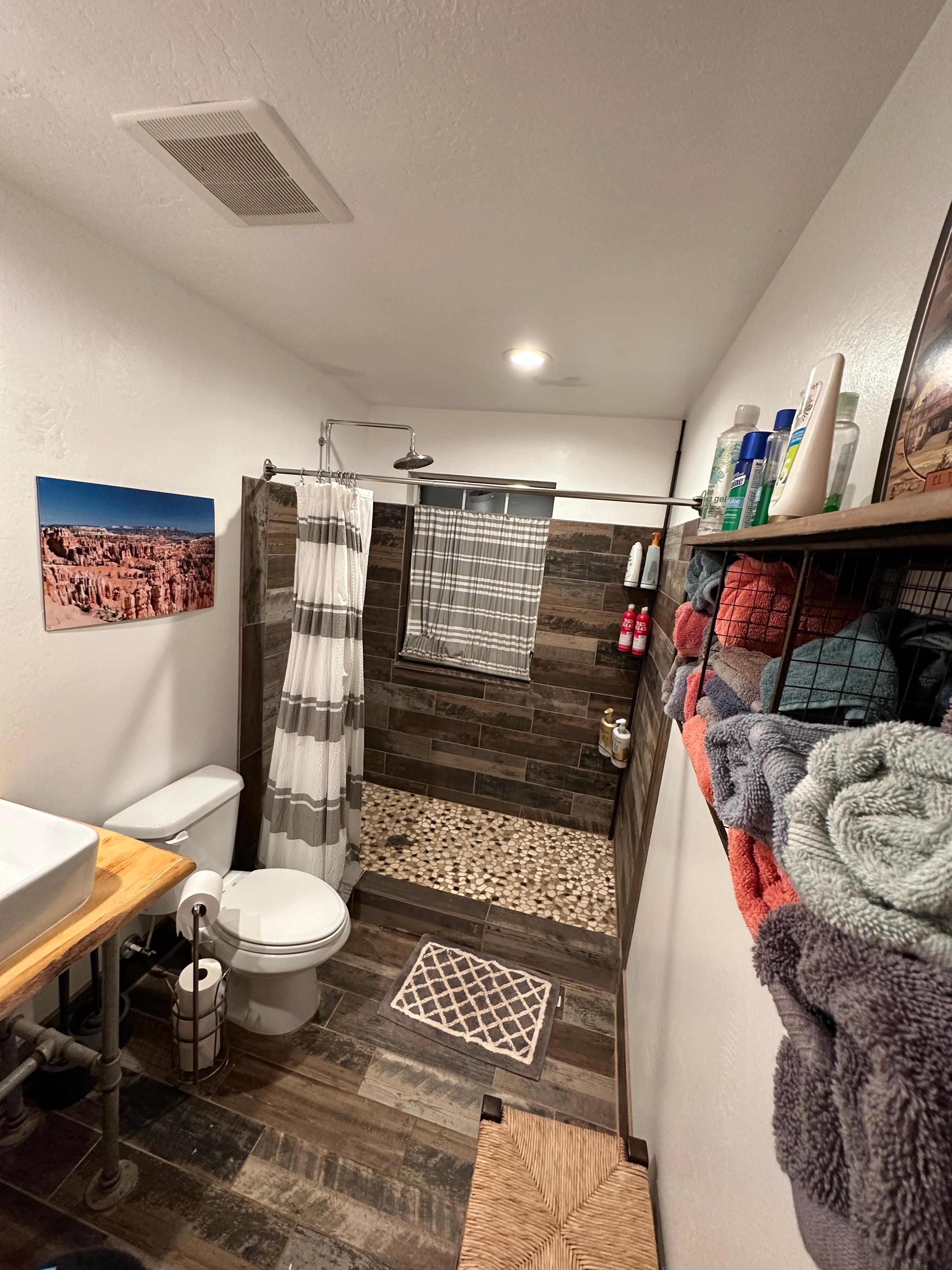 A clean bathroom with large shower fully stocked with shampoo and conditioner and clean towels. 