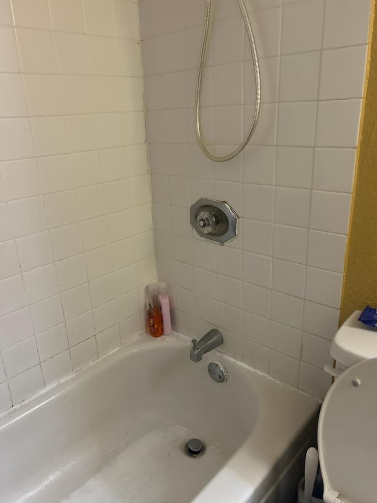Poorly patched and caulked tub with mildew laden grout. Please, zoom in.