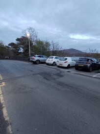 Very restricted shallow parking space, exposed to the traffic on the blinded curve road, also shoved with the trash bins, impossible to open the vehicle door,