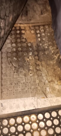 Floor under rubber mat behind bar.