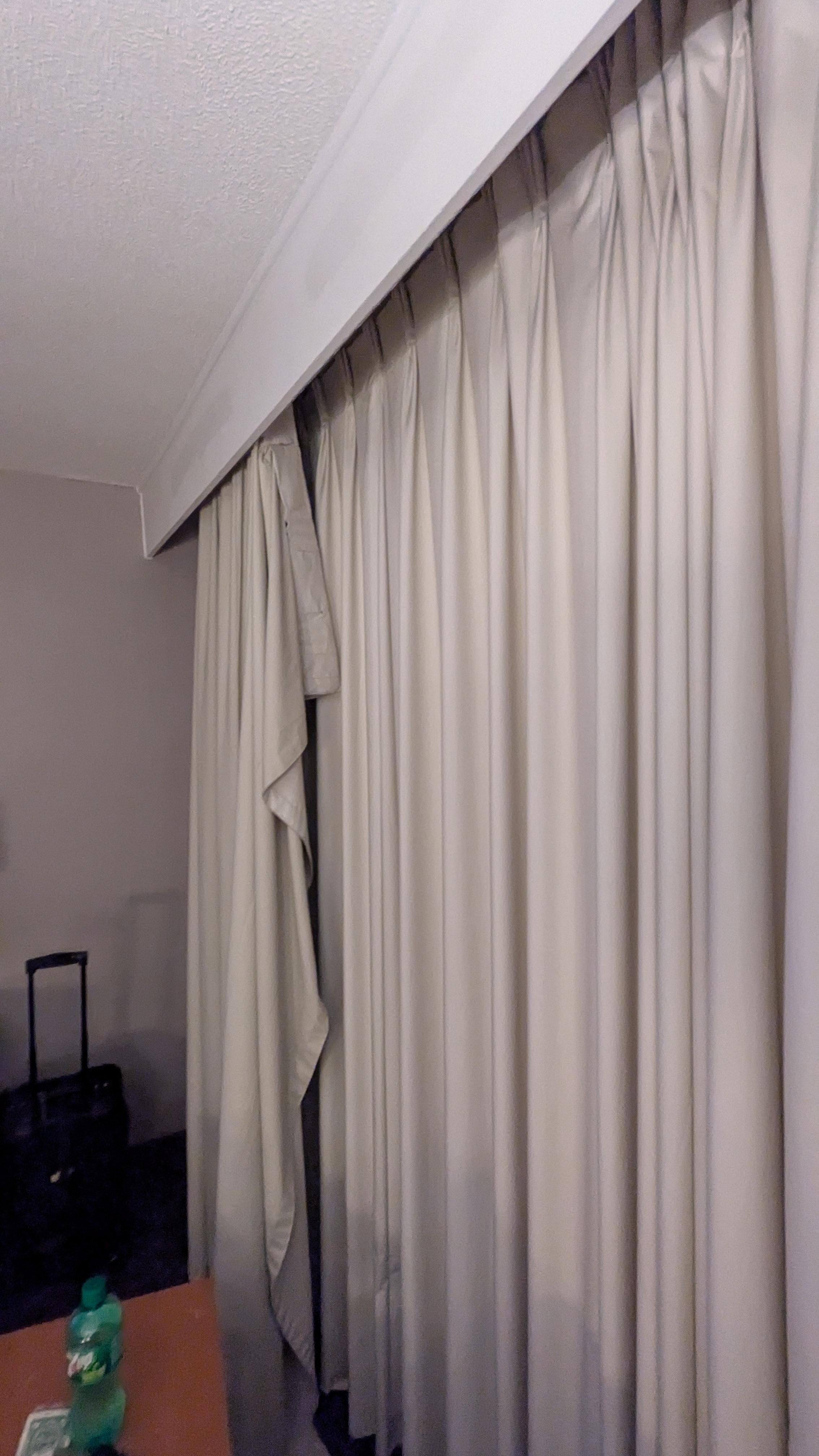 Old curtains not properly hung and left hanging 