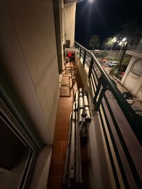 Cluttered balcony with broken furniture and cleaning supplies.