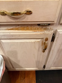 Very worn cabinets. This is where the trash can resides
