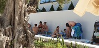 Personas ajenas al hotel que se resguardan a la sombra de la pared del hotel que da a la zona playa