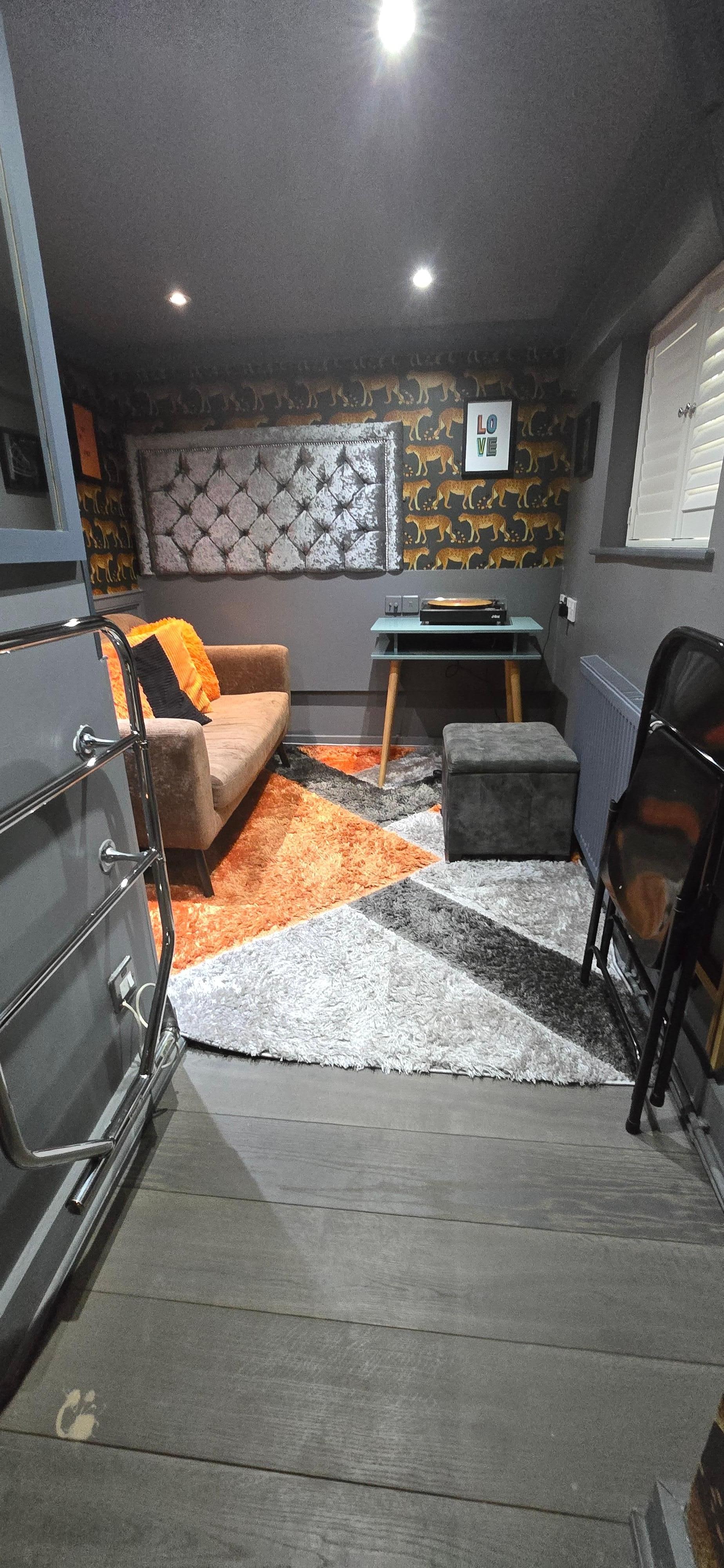 Living room w a TV & a record player. Very small windows.