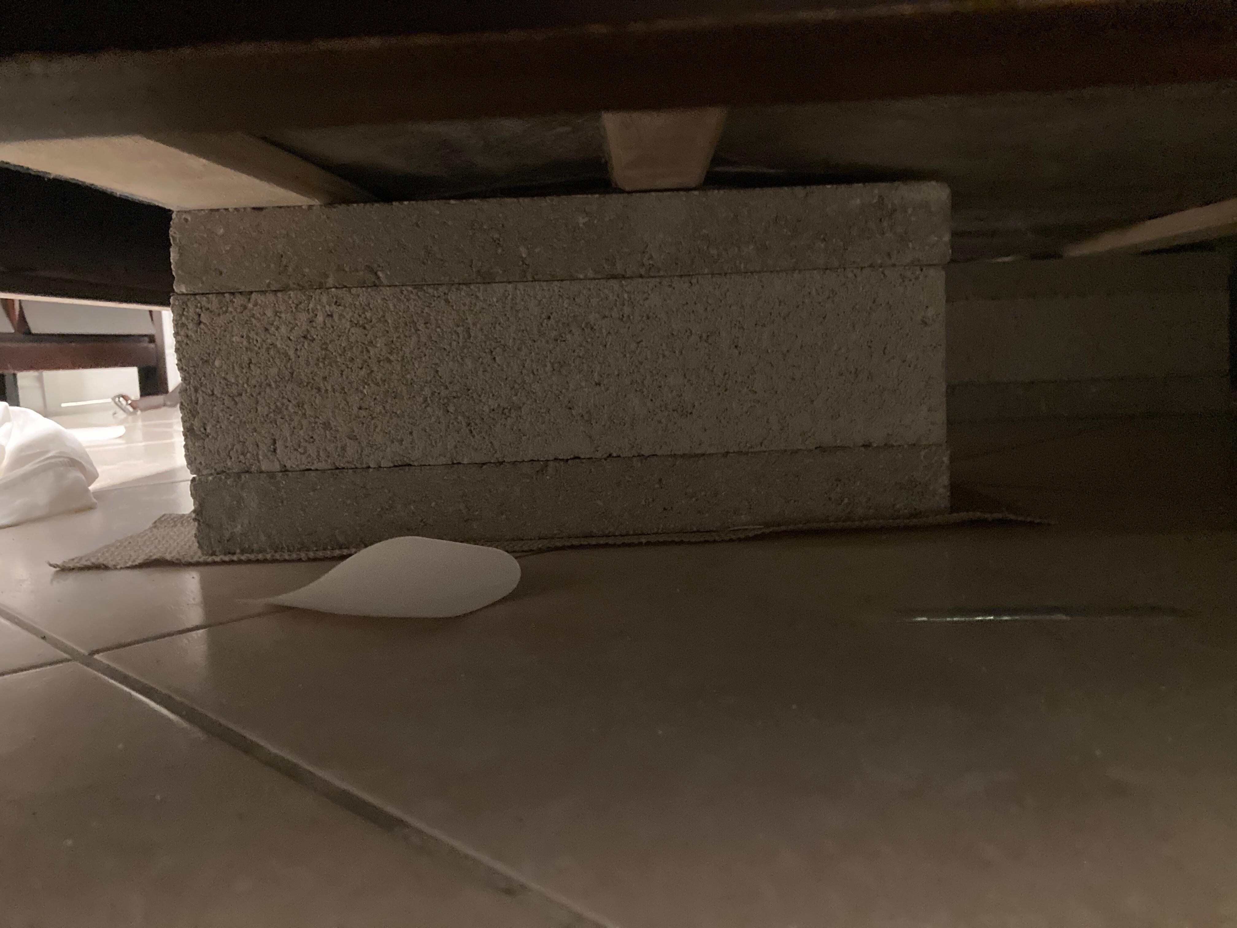 Broken bed held up with cinder block