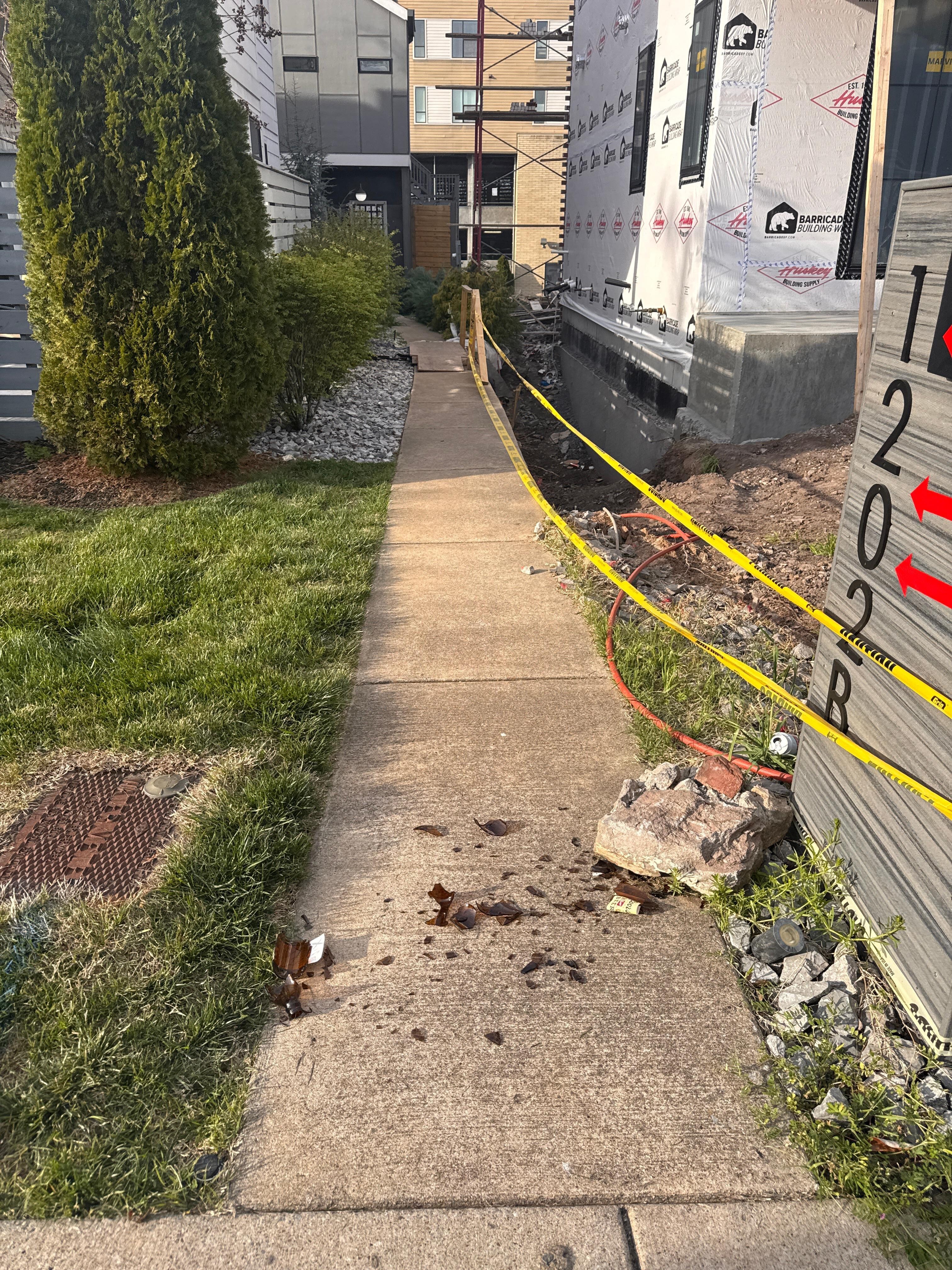 Treacherous front walkway. Sketchy trench next to the walkway, broken beer bottle