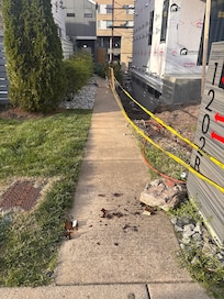 Treacherous front walkway. Sketchy trench next to the walkway, broken beer bottle