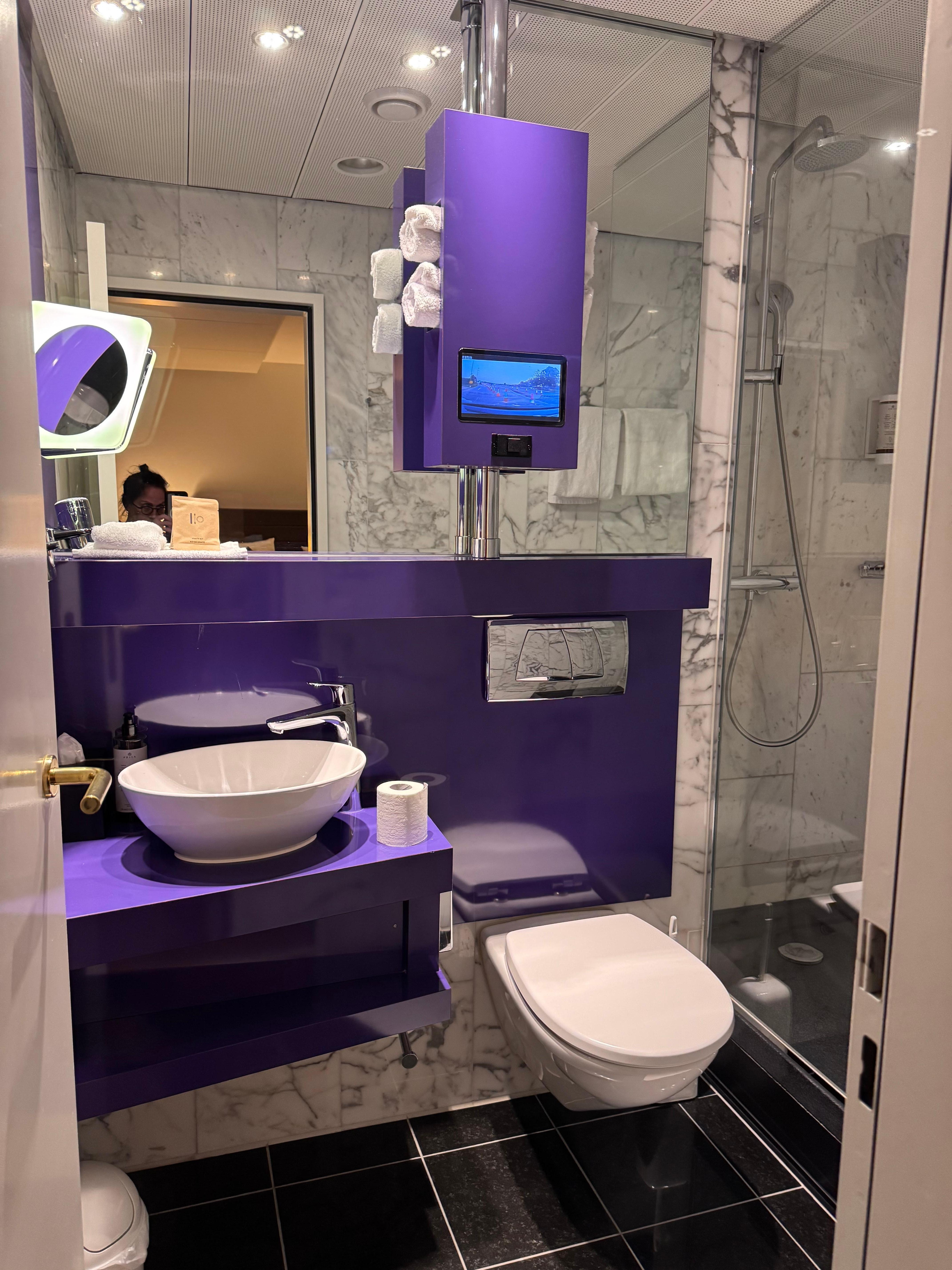 Purple bathrooms with TV’s is a real thing! *chefskiss*