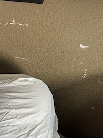 Splatters of something brown by the head of the bed